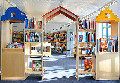 Tor-artiger Durchgang aus Bücherregalen als Eingang zum Kinderbereich einer Bücherei.